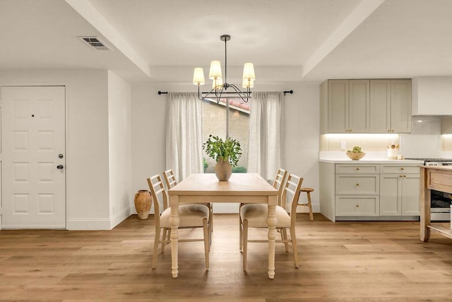 dining space featuring light hardwood / wood-style floors, a tray ceiling, and a chandelier