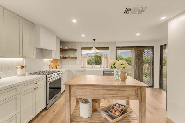 kitchen featuring light hardwood / wood-style floors, appliances with stainless steel finishes, decorative backsplash, decorative light fixtures, and sink