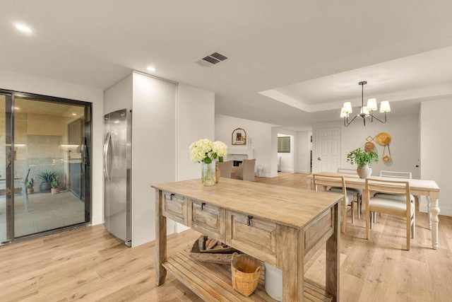 kitchen featuring decorative light fixtures, stainless steel refrigerator, an inviting chandelier, light wood-type flooring, and wood counters