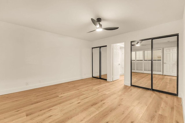 unfurnished bedroom featuring ceiling fan, light wood-type flooring, and two closets