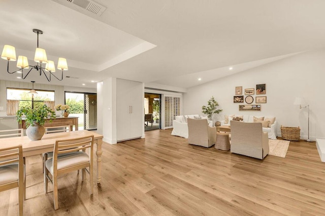 dining space with light wood-type flooring and a notable chandelier