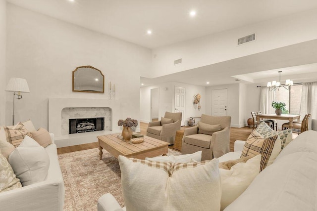 living room with a fireplace, a notable chandelier, and light hardwood / wood-style flooring