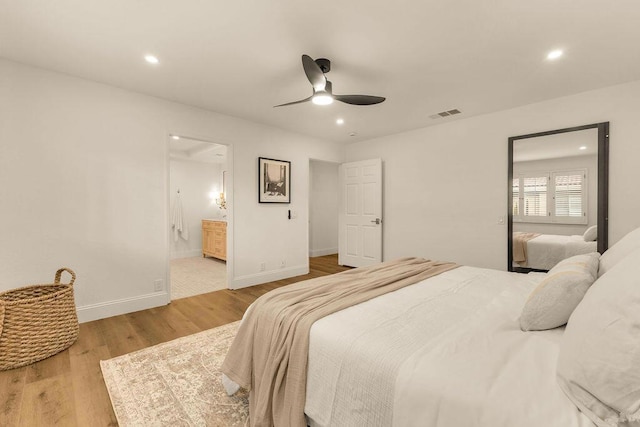 bedroom featuring ceiling fan, ensuite bath, and light wood-type flooring