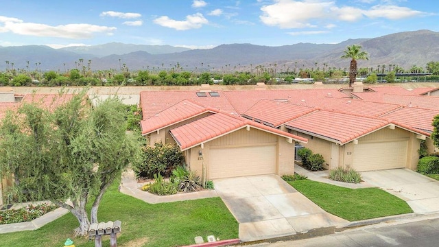 view of front facade featuring a front lawn, a mountain view, and a garage