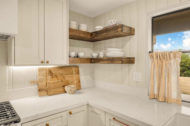 kitchen with white cabinets, light stone counters, and stovetop