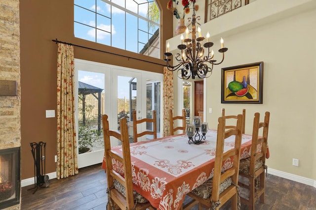 dining area featuring a notable chandelier, a towering ceiling, plenty of natural light, and dark hardwood / wood-style floors