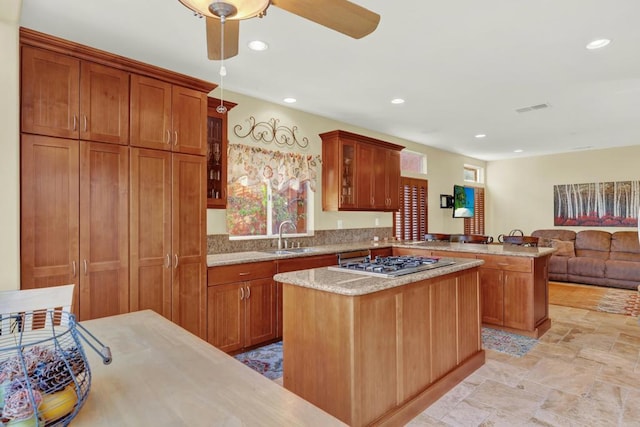 kitchen featuring sink, a kitchen island, kitchen peninsula, and stainless steel gas cooktop