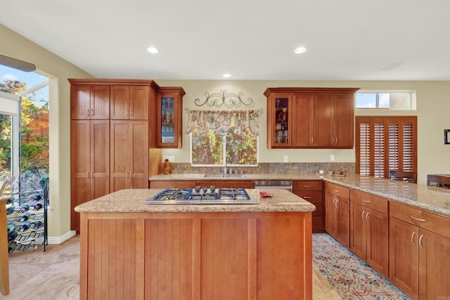 kitchen featuring light stone countertops, stainless steel appliances, sink, and a kitchen island