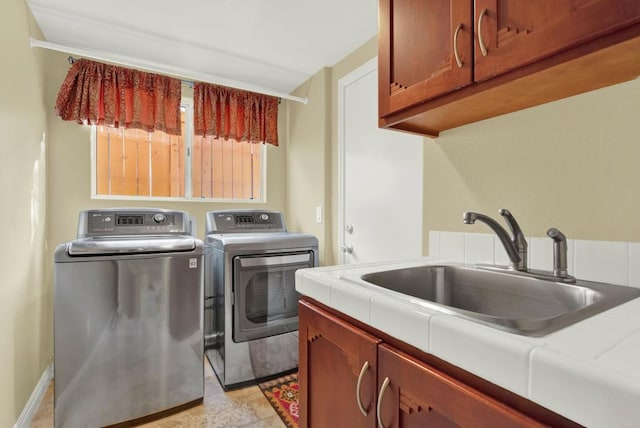 clothes washing area with cabinets, sink, and independent washer and dryer