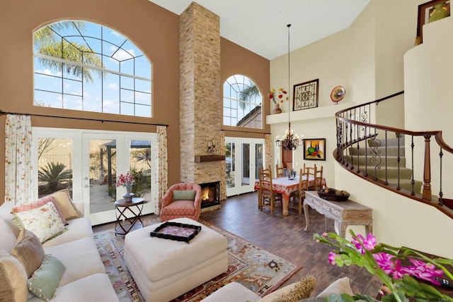 living room with an inviting chandelier, a fireplace, dark wood-type flooring, and french doors