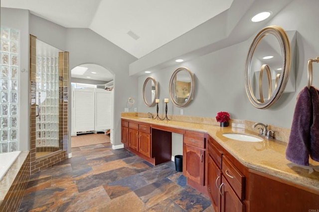 bathroom featuring lofted ceiling, a bath, and vanity