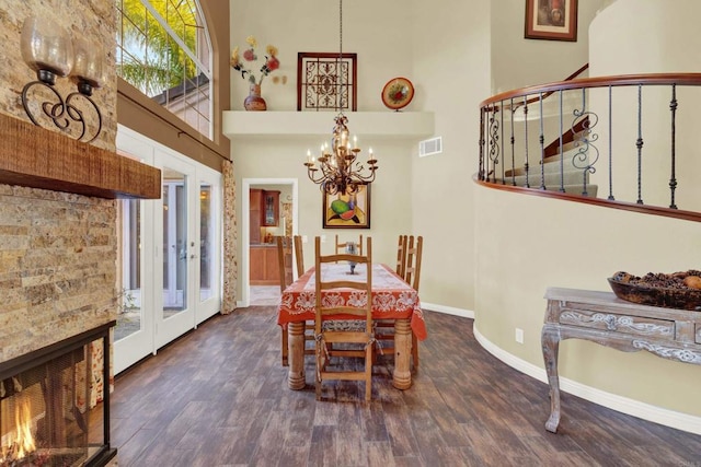 dining area with dark wood-type flooring, an inviting chandelier, and a towering ceiling