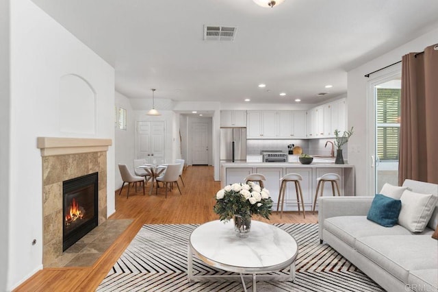 living room featuring sink, a fireplace, and light wood-type flooring