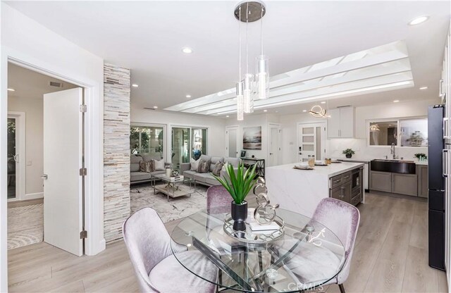 dining room featuring sink, an inviting chandelier, and light hardwood / wood-style flooring