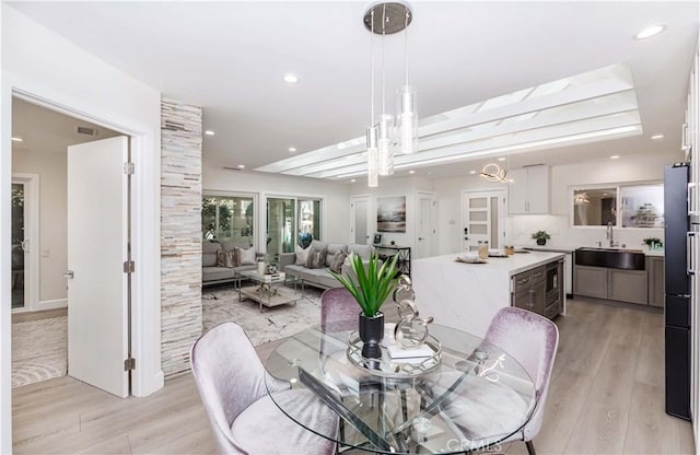 dining area featuring sink, an inviting chandelier, and light hardwood / wood-style flooring