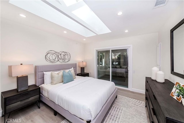 bedroom with light hardwood / wood-style flooring, access to exterior, and a skylight