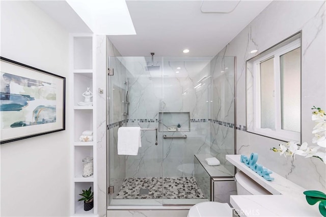 bathroom with a shower with shower door, built in features, and toilet