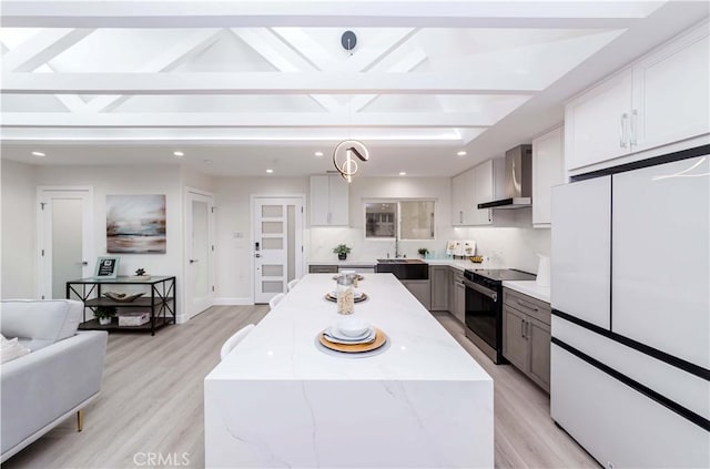 kitchen with white refrigerator, hanging light fixtures, light stone countertops, wall chimney range hood, and electric stove