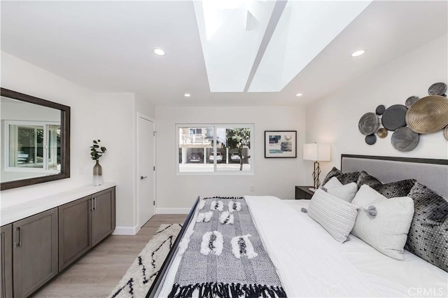 bedroom with a skylight and light hardwood / wood-style flooring