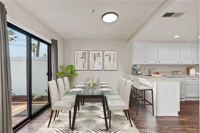 dining area with a textured ceiling, dark hardwood / wood-style floors, and sink