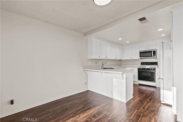 kitchen featuring a kitchen bar, kitchen peninsula, white cabinets, white gas range oven, and sink