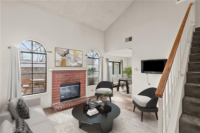 living room featuring a textured ceiling, a fireplace, wood-type flooring, and high vaulted ceiling