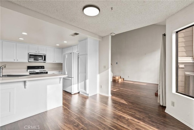 kitchen featuring white appliances, white cabinets, kitchen peninsula, and a textured ceiling