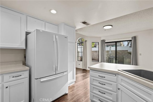 kitchen featuring white fridge, dark wood-type flooring, a textured ceiling, and white cabinets