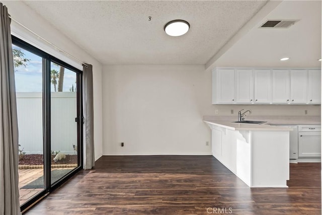 kitchen with dishwasher, kitchen peninsula, sink, a textured ceiling, and white cabinets