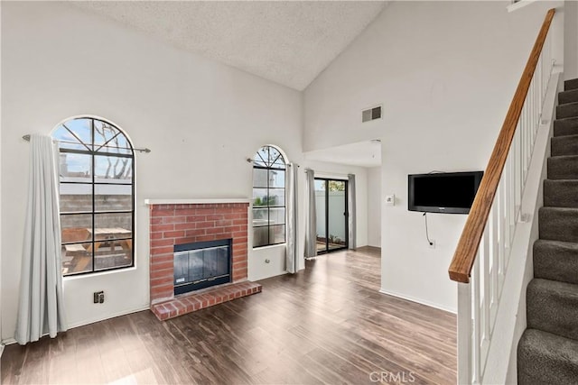 living room with a textured ceiling, hardwood / wood-style floors, and high vaulted ceiling