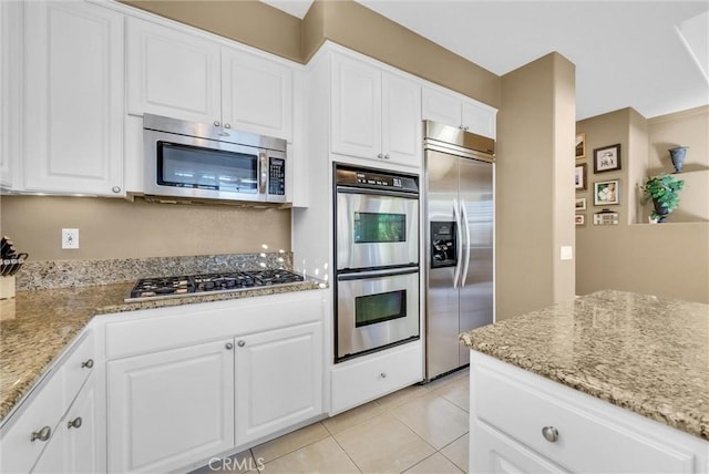 kitchen featuring light stone counters, light tile patterned floors, white cabinetry, and appliances with stainless steel finishes