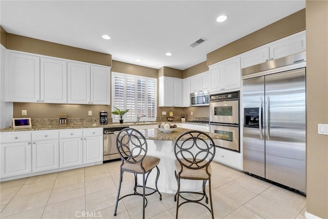 kitchen featuring white cabinets, light stone counters, and stainless steel appliances