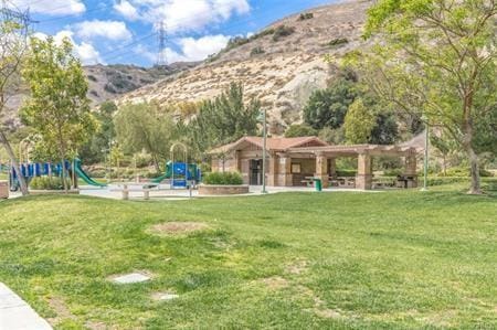 view of community featuring a playground, a lawn, and a mountain view