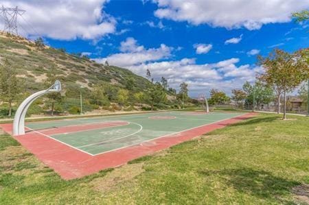 view of sport court with a mountain view and a yard