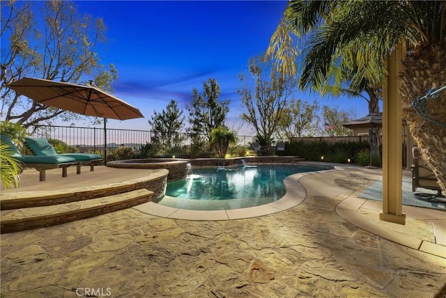 pool at dusk with a patio area and an in ground hot tub