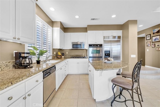 kitchen with white cabinets, sink, light stone counters, and stainless steel appliances