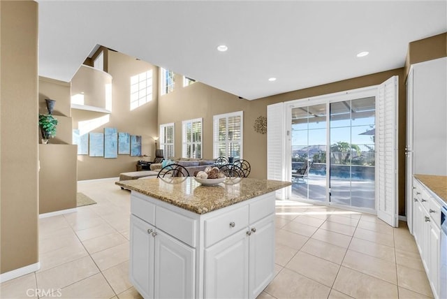 kitchen featuring white cabinets, light stone counters, light tile patterned floors, and a kitchen island