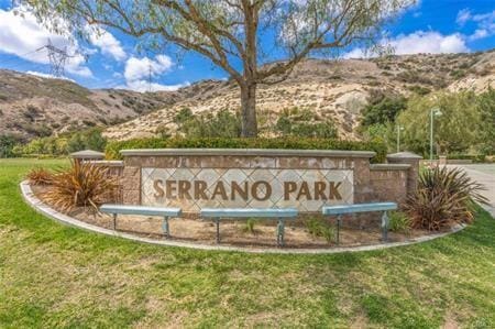 community / neighborhood sign featuring a mountain view and a yard