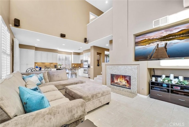 tiled living room with a healthy amount of sunlight, a tile fireplace, and a high ceiling