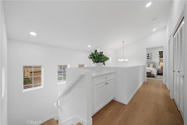 hall featuring lofted ceiling, an inviting chandelier, and light hardwood / wood-style floors