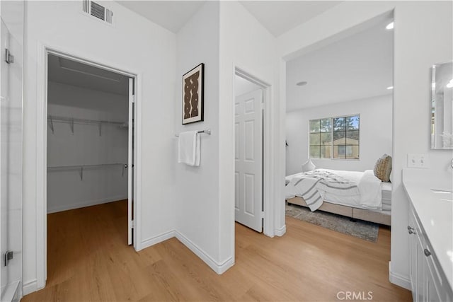 bedroom with a closet, a walk in closet, and light hardwood / wood-style floors