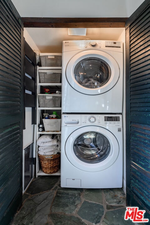 clothes washing area featuring stacked washer and clothes dryer