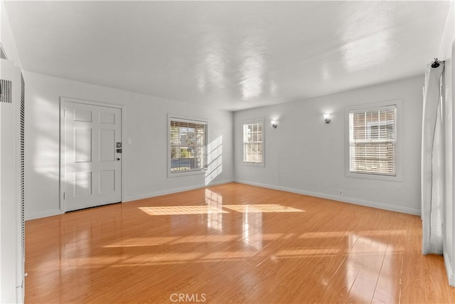 unfurnished living room featuring plenty of natural light and light hardwood / wood-style floors