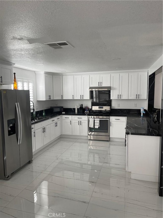 kitchen with white cabinetry, stainless steel appliances, sink, and a textured ceiling