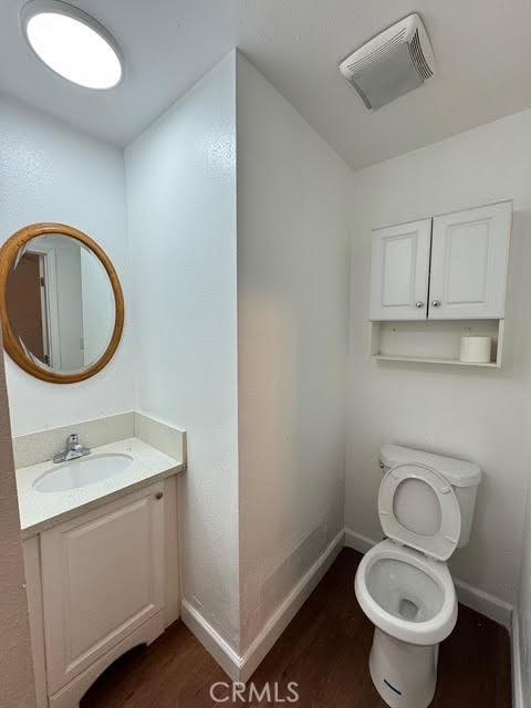 bathroom with vanity, wood-type flooring, and toilet