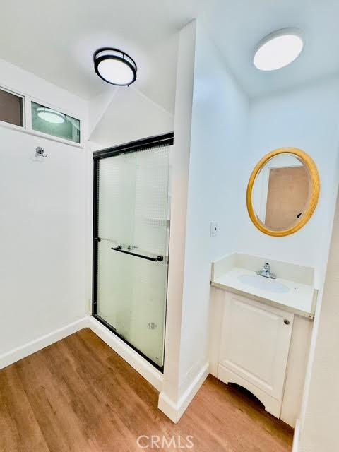 bathroom featuring wood-type flooring, an enclosed shower, and vanity