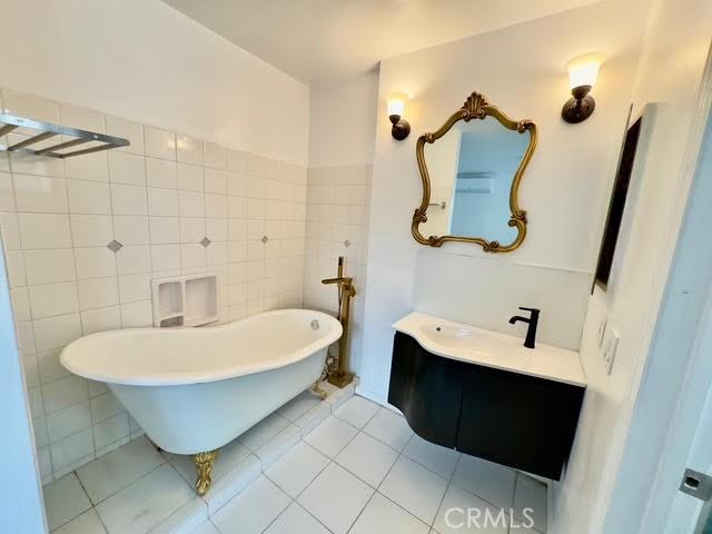 bathroom featuring tile walls, a tub to relax in, tile patterned flooring, and vanity