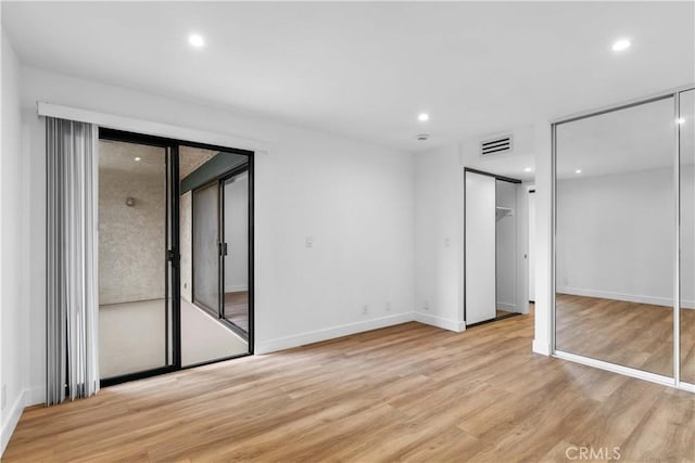 unfurnished bedroom featuring light hardwood / wood-style floors and a barn door