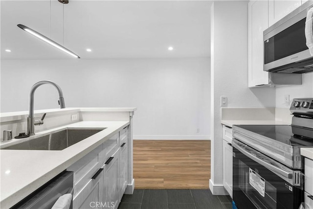 kitchen featuring appliances with stainless steel finishes, pendant lighting, white cabinetry, and sink