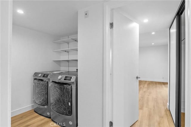 laundry room with light hardwood / wood-style floors and washing machine and clothes dryer